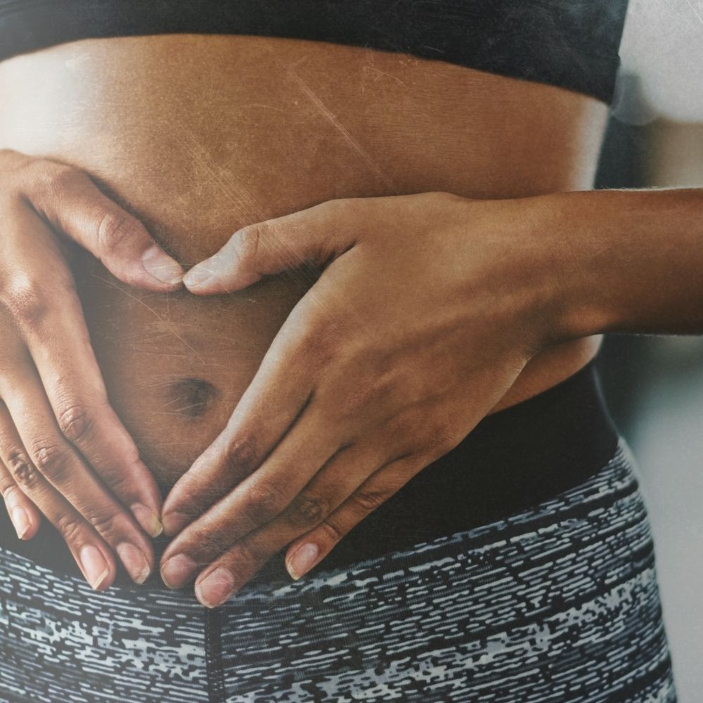 Picture of a lady in gym gear holding her hands in a heart shape over her stomach this image depicts how apple cider vinegar with the mother in it can be good for digestion