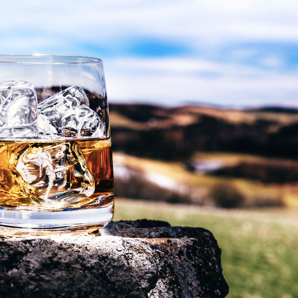Scottish Whisky glass in the Scottish countryside. Scotch on the rocks.