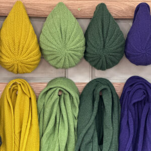 infinity scarf and slouch hats hanging on a peg rail made from supersoft Scottish Lambswool in this blog post learn how to care for your scottish knitwear