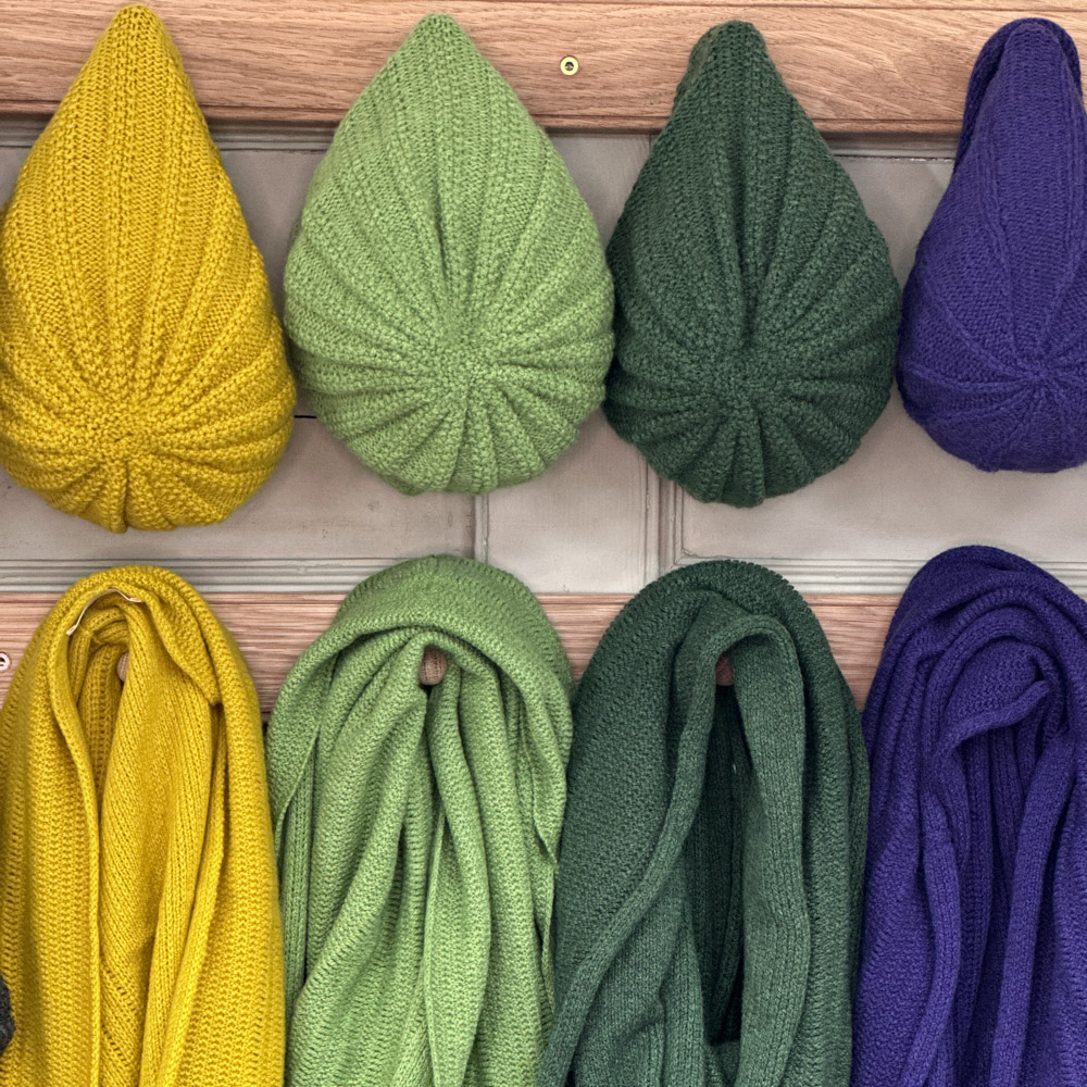 infinity scarf and slouch hats hanging on a peg rail made from supersoft Scottish Lambswool in this blog post learn how to care for your scottish knitwear