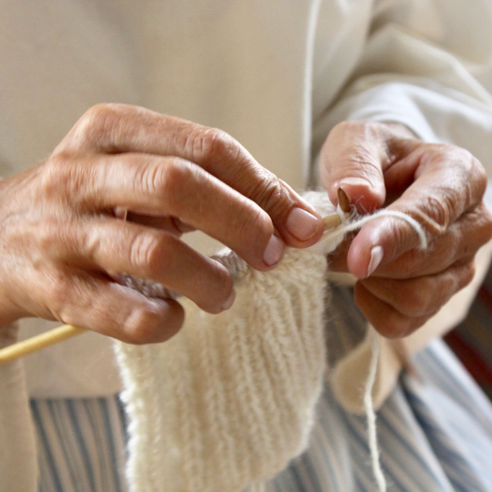 older lady knitting a lambswool hat