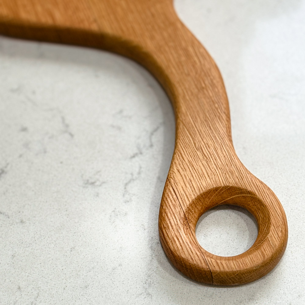 reclaimed oak whisky lid paddle board with unique handle, displaying a slice of banana cake on a napkin, and vintage crockery nearby