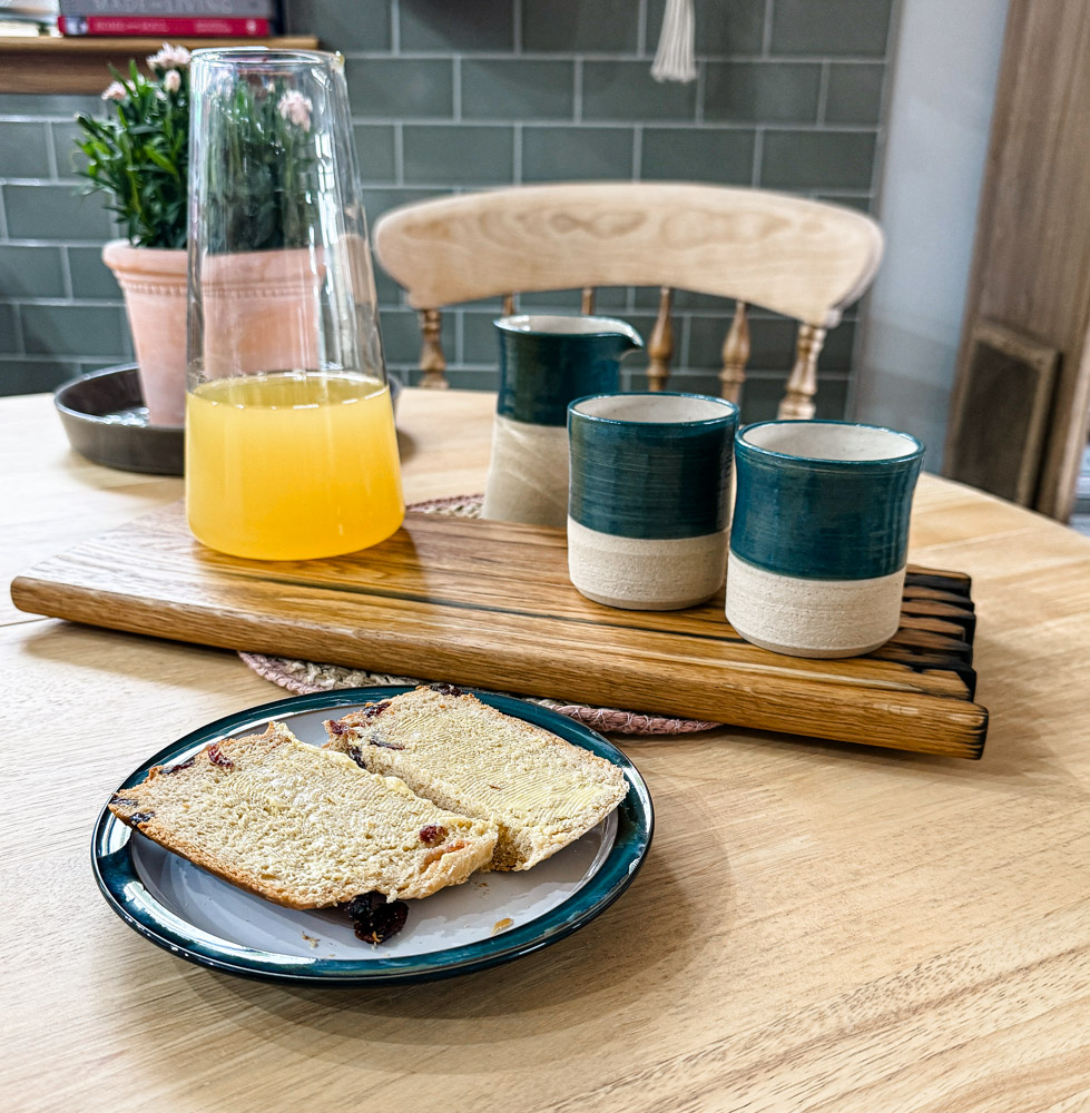 Handcrafted whisky stave chopping board on a wooden table, styled with a jug and part glazed blue beakers, highlighting the rich wood grain and artisanal craftsmanship