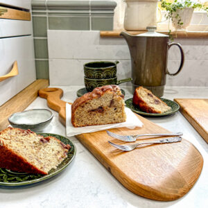 reclaimed oak whisky cask lid paddle board with unique handle, displaying a slice of banana cake on a napkin, and vintage crockery nearby. the paddle board is made in Scotland