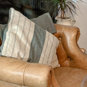 Scottish wool fabric and scottish linen fabric cushions in a muted teal and railroad stripe in a brown leather armchair