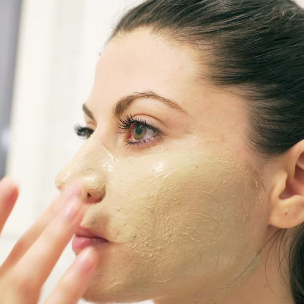 lady spreading refine and balance onto face as a facial masque she is using her fingers to gently spread the mask onto her face