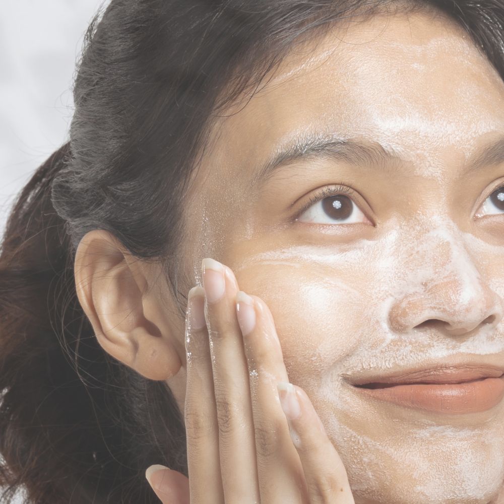 Balance oil cleanser and purifying facial masque combined for a deep cleanse being massaged into the face on a beautiful woman with dark hair