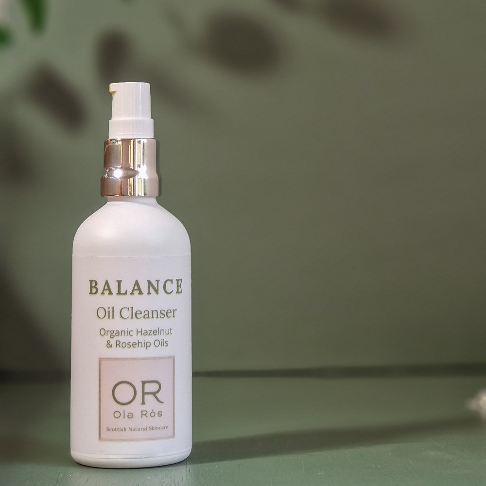 balance oil cleanser in white matte glass bottle against green background