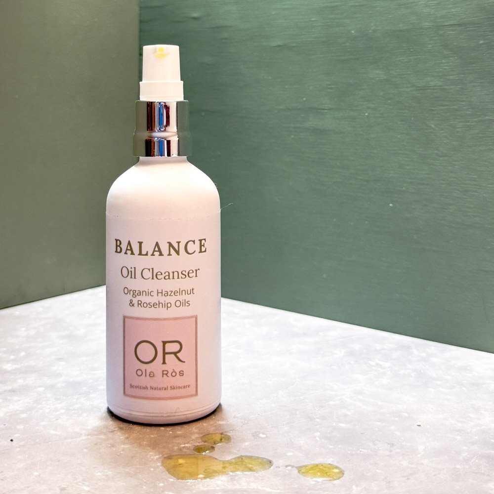 balance oil cleanser in white matte glass bottle against green background a few drops of oil are on the grey worktop beside the bottle Handmade in Scotland Scottish Skincare