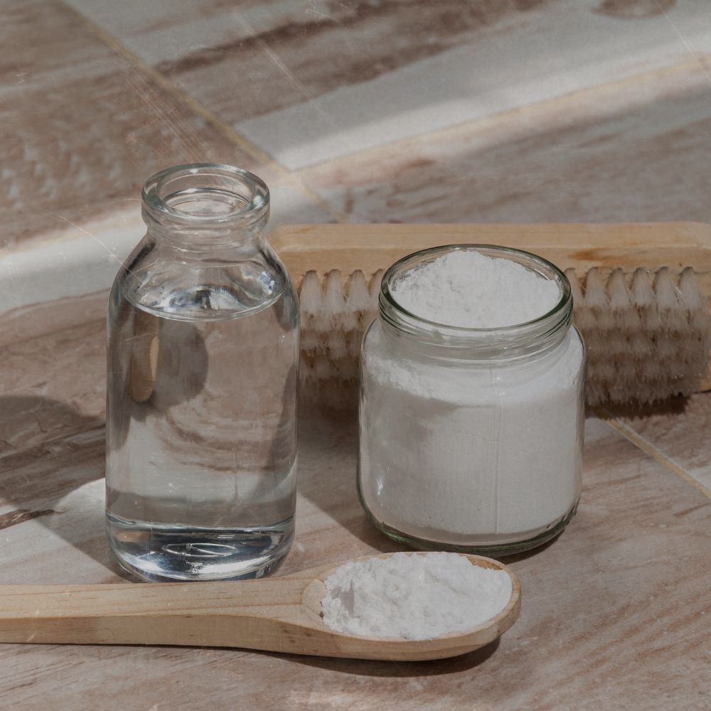 a bottel of white vinegar and a tub of bicarbonate of soda ready to make a fizz cleaner for sinks and drains, limescale and grease