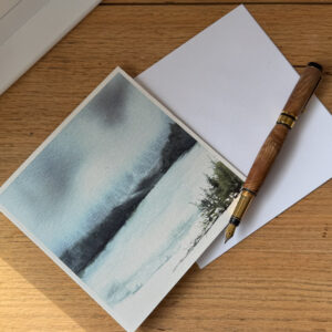 Loch Ness watercolour greeting card by Julia Anne displayed with a matching envelope, highlighting UK printing in a square 150mm format.