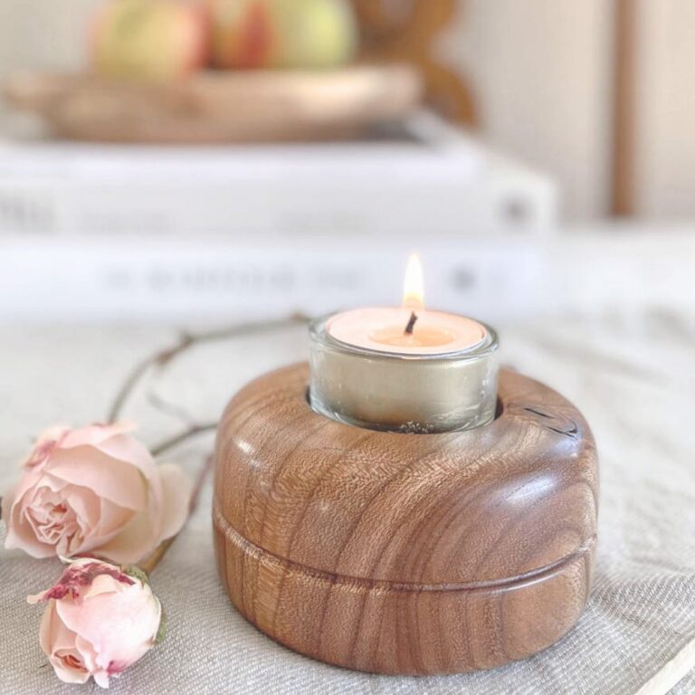Handmade tealight holder in scottish elm with lit tealight inside sat on a table with a linen tablecloth and two pink roses laid beside